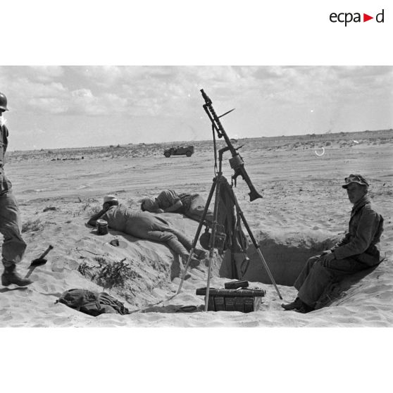 Les servants d'une mitrailleuse MG-34, installée sur un affût tripode pour le tir anti-aérien, se reposent.