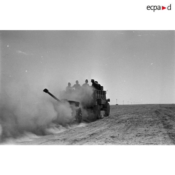 Dans un nuage de poussière, un camion Ford 3T d'origine britannique tracte un canon antichar (5 cm PaK 38).