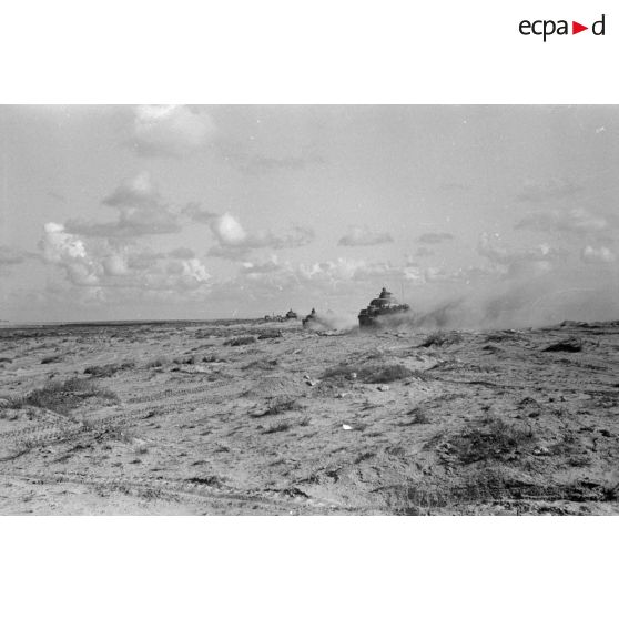 Les nuages de poussière dégagés par les véhicules et les explosions vus d'un trou de tirailleur.