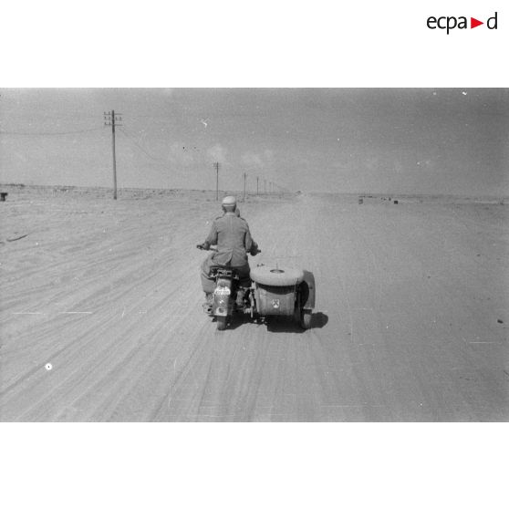 Un side-car BMW R75 roule dans le désert, le long de la piste baptisée du télégraphe.