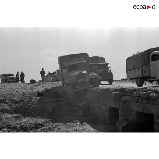 Passage d'un pont par une colonne de véhicules allemands et italiens, un camion accidenté a glissé hors du pont.