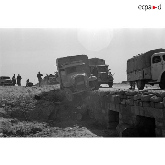 Passage d'un pont par une colonne de véhicules allemands et italiens, un camion accidenté a glissé hors du pont.