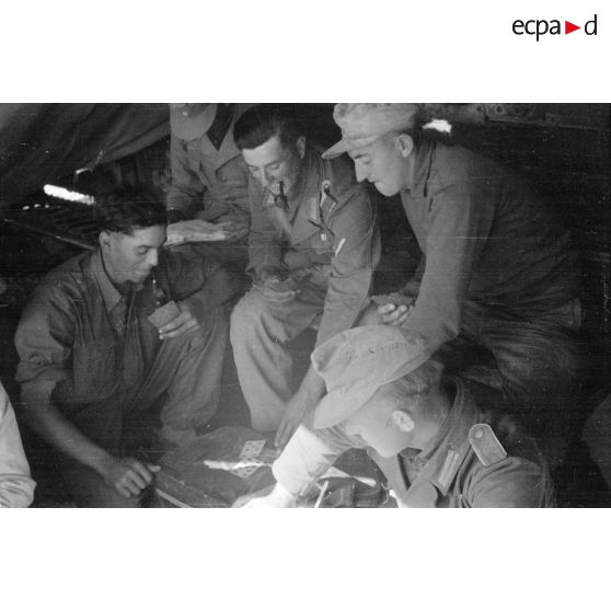 Moment de détente dans un abri pour des soldats allemands. Jeu d'échec et accordéon. Repas.