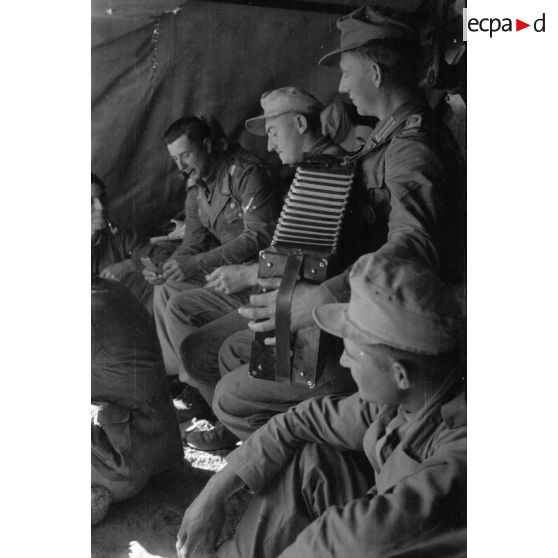 Moment de détente dans un abri pour des soldats allemands. Jeu d'échec et accordéon. Repas.