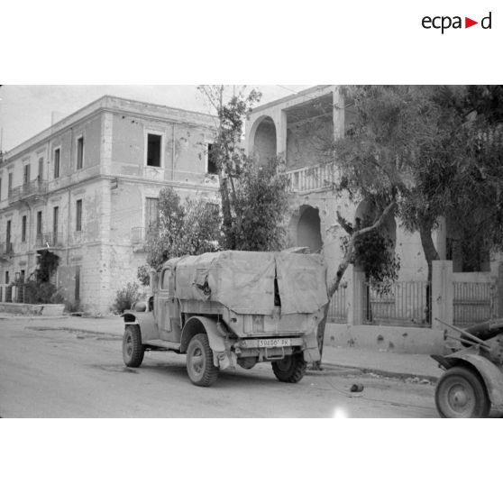 Plusieurs véhicules dont une voiture Kübelwagen garés près du bâtiment servant au journal du front Die Oase.