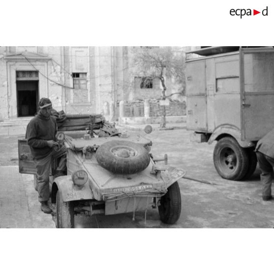 Plusieurs véhicules dont une voiture Kübelwagen garés près du bâtiment servant au journal du front Die Oase.