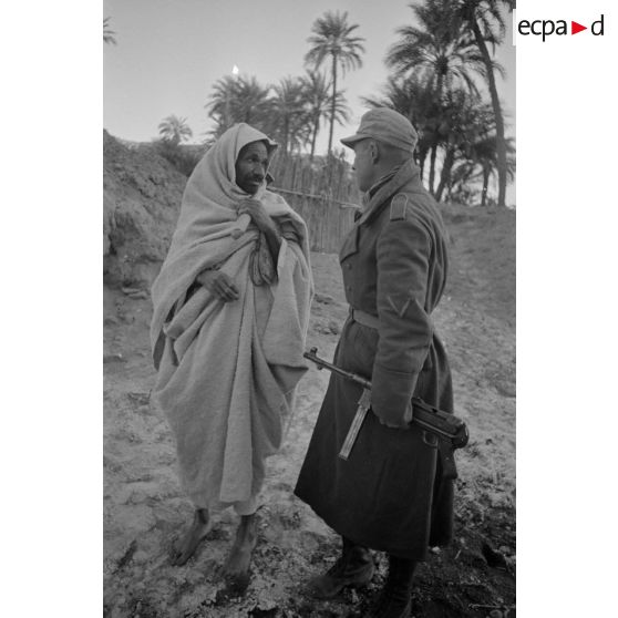 Un officier et un caporal (Gefreiter), tous deux armés de MP-40, parlent avec un paysan libyen.