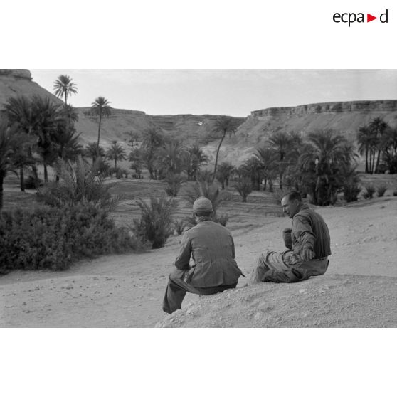 Un lieutenant (Oberleutnant) et un caporal (Gefreiter) assis, regardent passer des enfants, avec un mulet et avec un dromadaire.