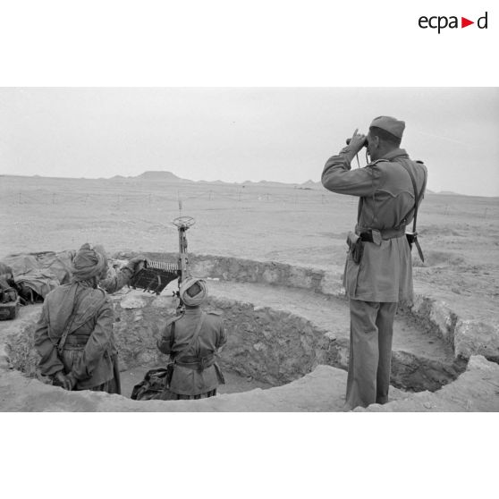 Alvéole occupée par une mitrailleuse Breda modèle 1937 en version antiaérienne. Un officier observe le terrain à la jumelle.