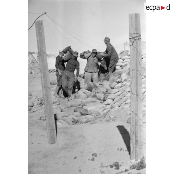 Deux soldats transportent des sacs de sable.