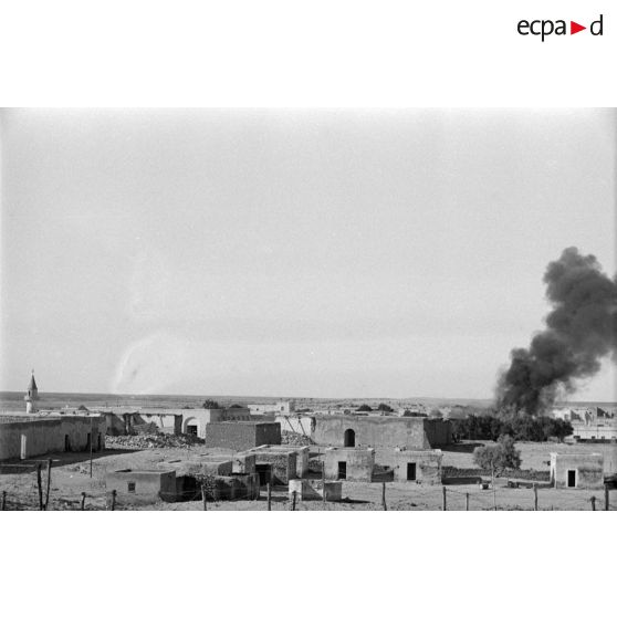 Vue générale d'un village d'où se dégage un nuage de fumée.