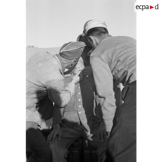 Un Oberleutnant, aidé par un Oberfeldwebel, soigne plusieurs blessés légers.