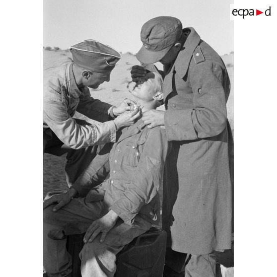 Un Oberleutnant, aidé par un Oberfeldwebel, soigne plusieurs blessés légers.