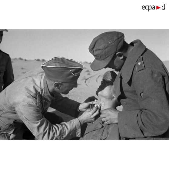 Un Oberleutnant, aidé par un Oberfeldwebel, soigne plusieurs blessés légers.