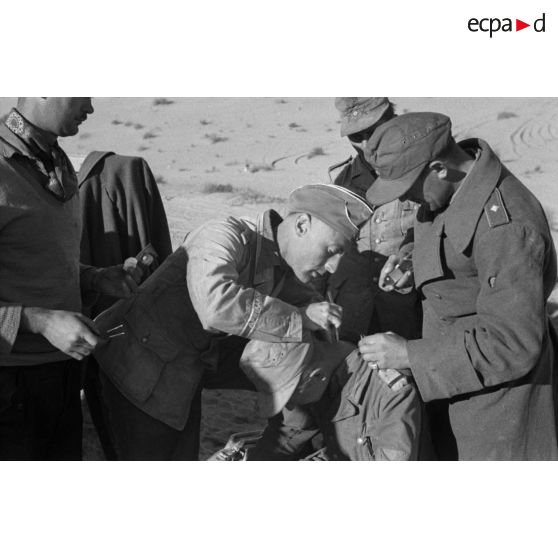 Un Oberleutnant, aidé par un Oberfeldwebel, soigne plusieurs blessés légers.