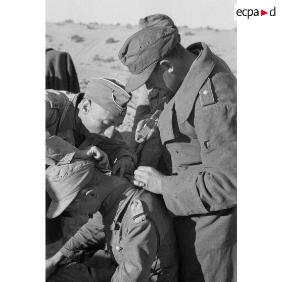 Un Oberleutnant, aidé par un Oberfeldwebel, soigne plusieurs blessés légers.