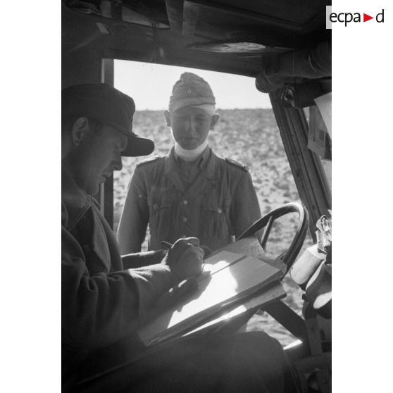 Un Oberleutnant des Sanitätstruppen établit un document dans la cabine d'un véhicule.