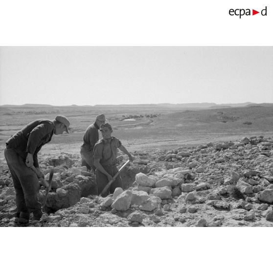 Des fantassins creusent des tranchées à flanc de colline.