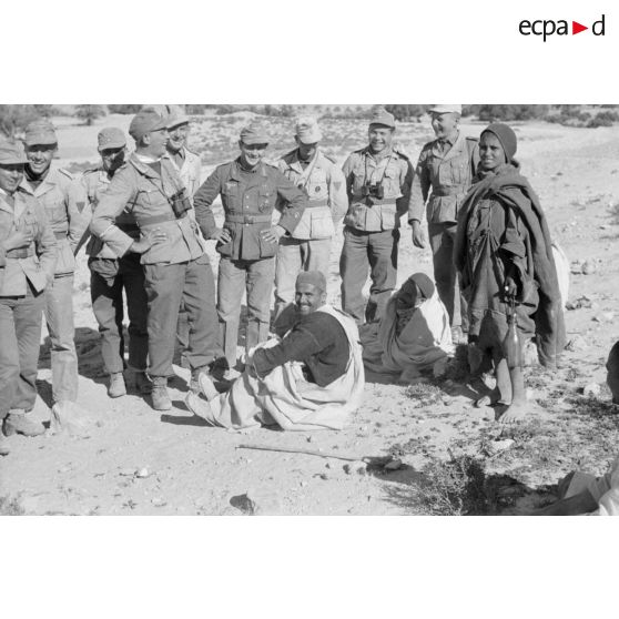 Un groupe de soldats entoure deux hommes et un jeune garçon.