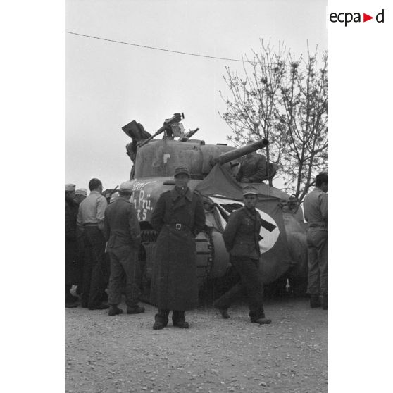 Des soldats allemands entourent un char américain M4A1 recouvert d'un drapeau et d'une inscription.