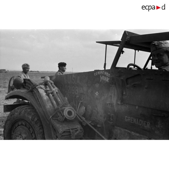 Avant d'un half-track américain (APC M2) capturé, un soldat allemand est au volant.