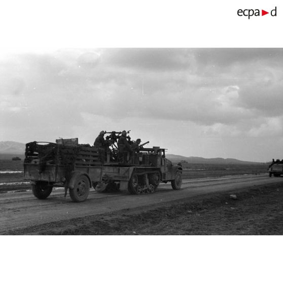 Passage d'un half-track (APC M2) de prise qui tracte une remorque américaine.