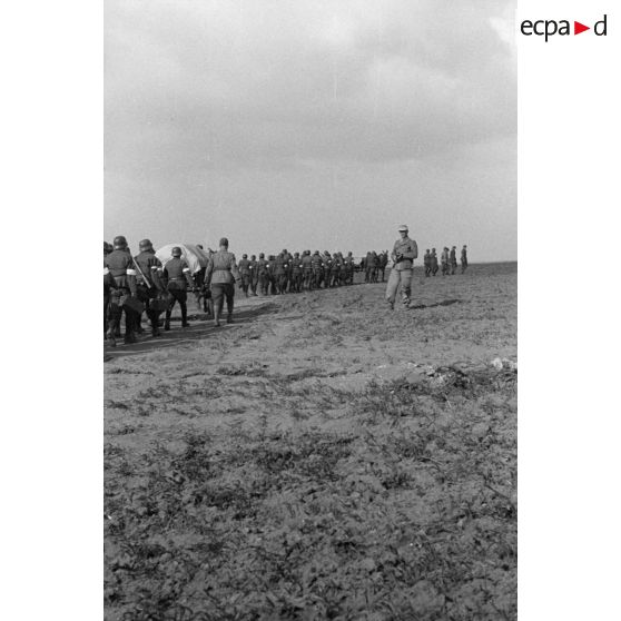 Les volontaires défilent en colonne devant un officier allemand.