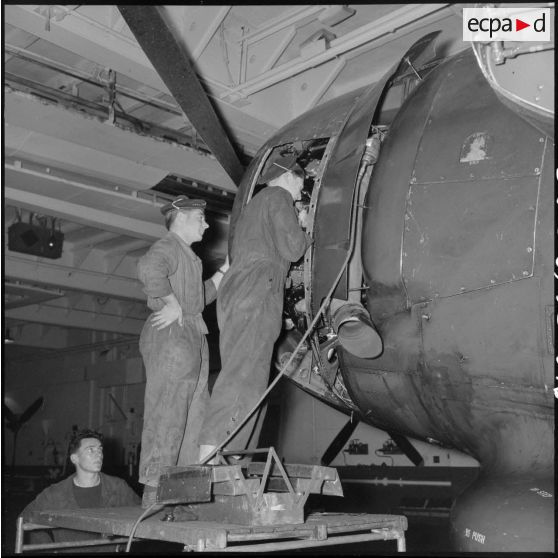 Maintenance du moteur d'un bombardier Grumman TBM-3S Avenger par des mécaniciens du porte-avions l'Arromanches lors d'un exercice en Méditerranée.