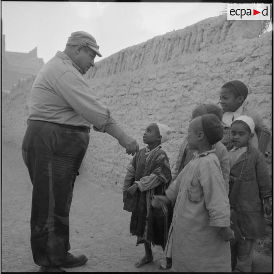 Gérard Py, photographe du Service cinématographique des Armées (SCA) jouant avec un groupe d'enfants algériens à Ghadamès.