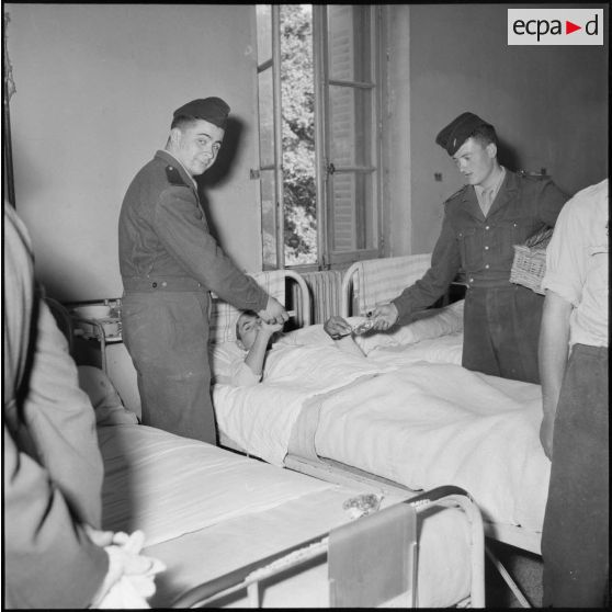 Distribution de cigarettes et de bonbons aux blessés de l'hôpital Maillot par des militaires du service social.