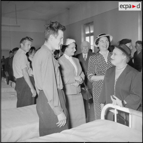 Madame Lacoste discutant avec un soldat blessé lors d'une visite à l'hôpital Maillot d'Alger.