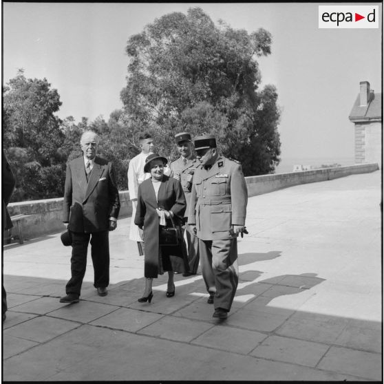 Madame Lacoste accompagnée d'autorités traversant la cour de l'hôpital Maillot à Alger.