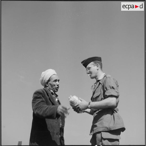 Homme kabyle offrant des confiseries à un soldat du 21e RIC (régiment d'infanterie coloniale) au poste de Tizi N'Berber.