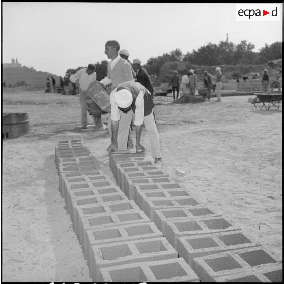 Alignement de parpaings par des ouvriers algériens sur le chantier de nouvelles habitations de Bou Ahra.