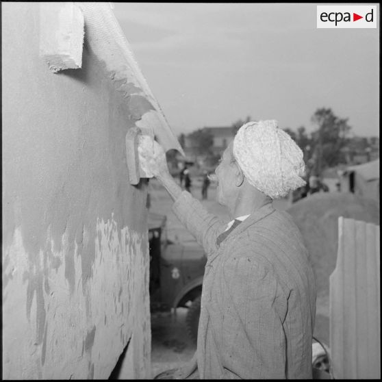 Crépissage des murs par un ouvrier algérien sur un chantier du village de Mondivi (Dréan).