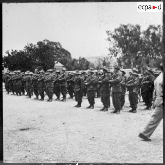 Troupes au présentez-armes lors d'une prise d'armes au camp de Laghouat pour la visite du secrétaire d'état aux forces armées Max Lejeune.