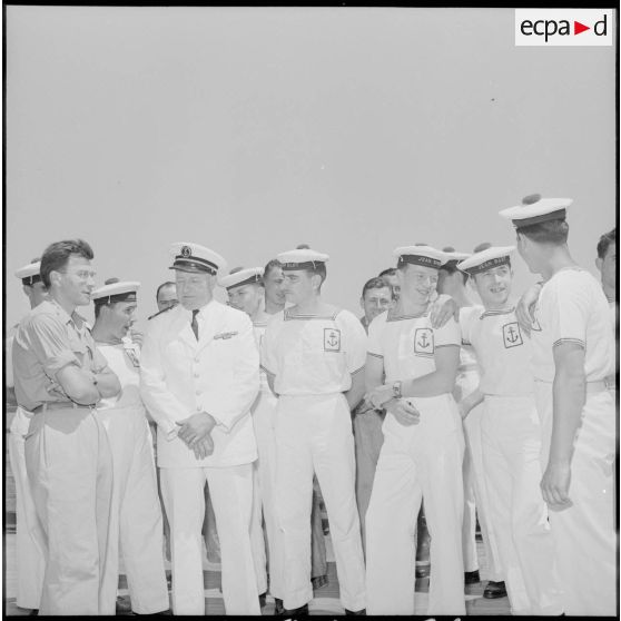 Un reporter militaire et un officier entourés de matelots du navire-école Jean Bart.