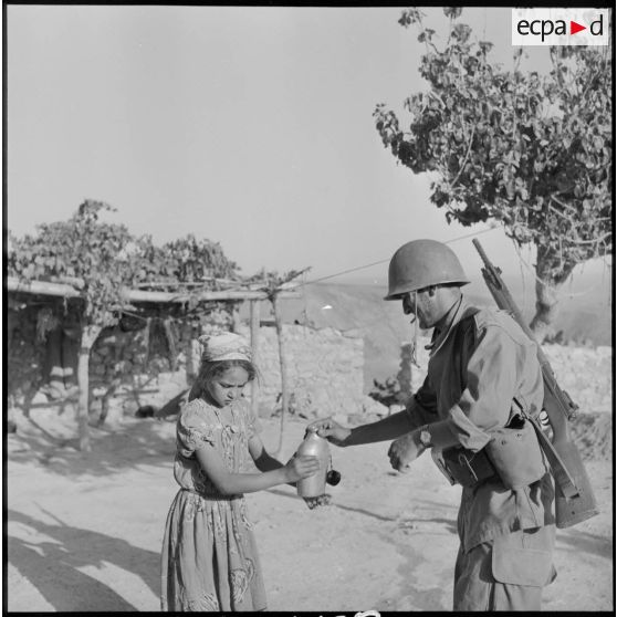 Une petite fille offrant à boire à un fusilier-marin du 2e bataillon de la 1re demi-brigade de fusiliers-marins (DBFM).