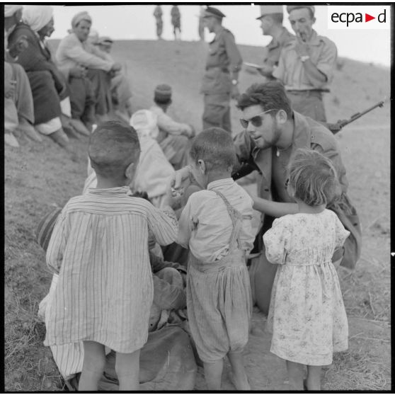 L'infirmier du 1er bataillon de la 1re demi-brigade de fusiliers-marins (DBFM) distribuant des bonbons aux enfants de Beni Menir.