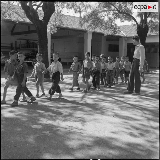 Main dans la main, en rang deux par deux, les jeunes élèves d'une école moderne de Bougie traversent la cour de l'école.