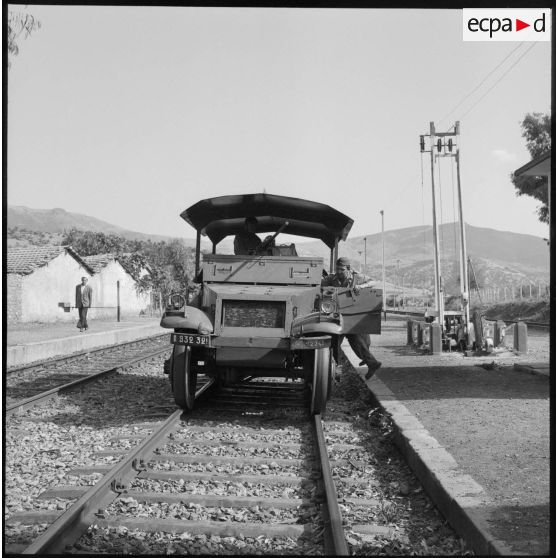 Un véhicule blindé stationne sur des rails de chemin de fer.