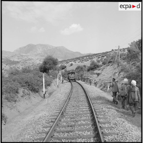 Un véhicule blindé patrouille sur des rails de chemin de fer.