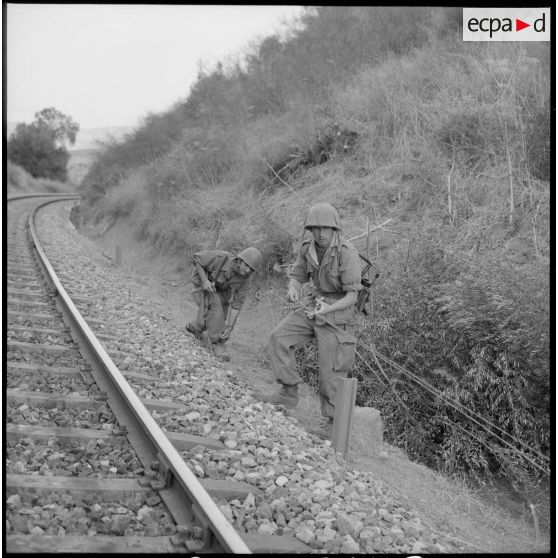 Deux soldats sécurisent les abords des voies de chemin de fer.