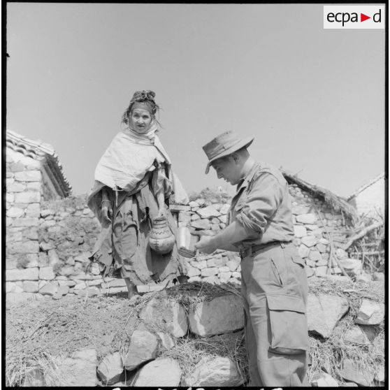 Une femme offre à boire à nos soldats.