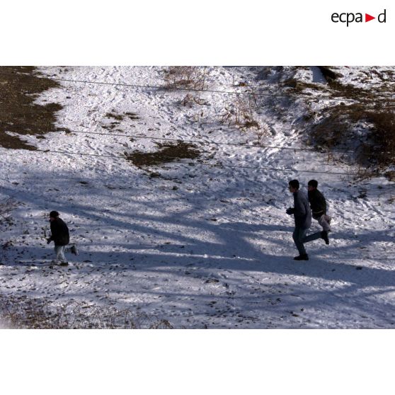 Des enfants courent dans la neige.