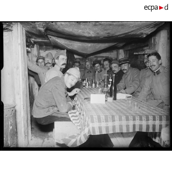 Bois de la Raquette, repas des officiers du 25e Régiment d'artillerie dans leur cagna. [légende d'origine]