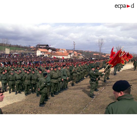 Les militaires de l'armée de libération du Kosovo (UCK) en rangs avec des drapeaux à l'emblème de l'armée de libération du Kosovo (UCK).