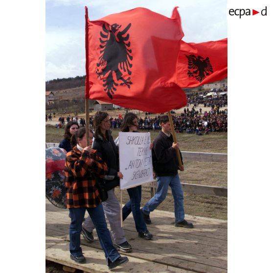 Des Kosovars défilent avec une banderole en hommage à la famille Jashari et des drapeaux de l'armée de libération du Kosovo (UCK).