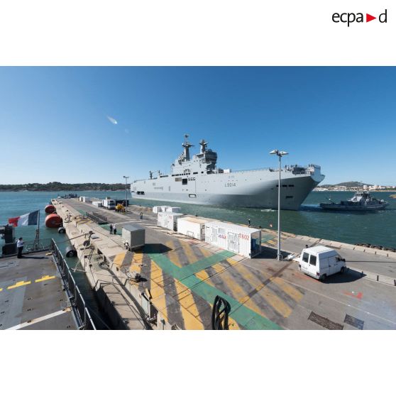 Le bâtiment de projection et de commandement (BPC) Le Tonnerre mouille aux côtés du remorqueur-pousseur Estérel à quai de la base navale de Toulon.