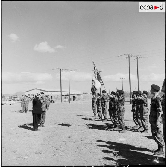 Le vice-amiral d'escadre Barjot salue le drapeau d'une unité parachutiste lors d'une cérémonie du 11 novembre au camp X (Chypre).